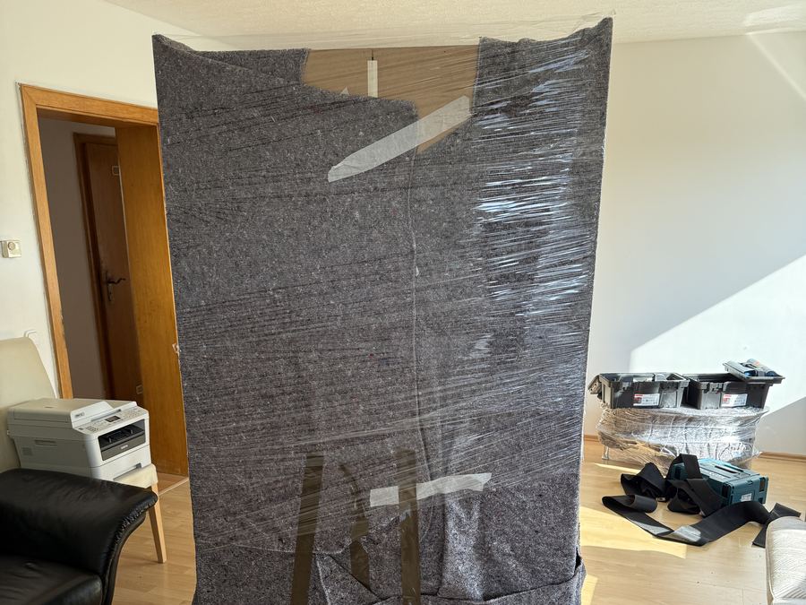 Ein Schrank, vollstaendig in Decken und Folie verpackt