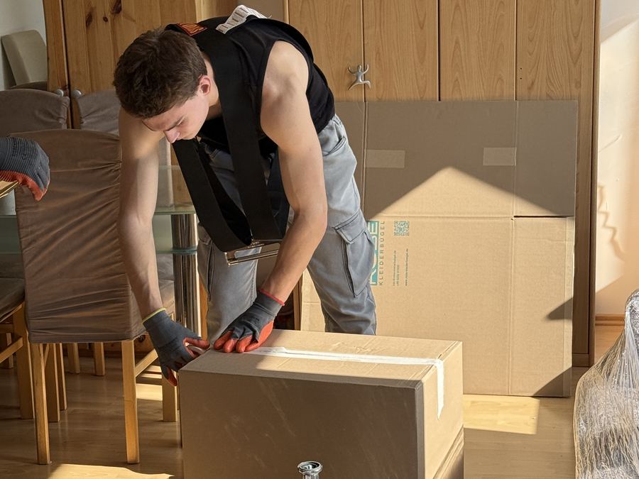 Umzugshelfer hebt einen gepackten Karton vorsichtig an